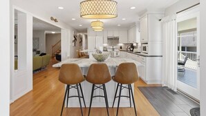 Una cocina moderna con una isla de mármol, iluminación colgante y vistas al exterior.