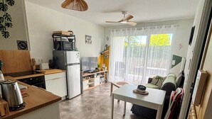 A compact kitchen with a refrigerator, microwave, and stove, a dining area with a table and chairs, and a ceiling fan. - ✨ Appartment 41 m² en rez-de-jardin - Vielle-Saint-Girons (Vielle-Saint-Girons)