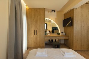 Ein modernes Hotelzimmer mit einem Bett, einem Holzschrank, einem Schminktisch mit Spiegel und einem an der Wand befestigten Flachbildfernseher.