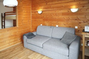 A wooden interior with a grey sofa, a ladder, and a toaster on a wooden table. - travelski home select - Résidence Le 1650 - Studio 4 personnes 409 (Les Orres)