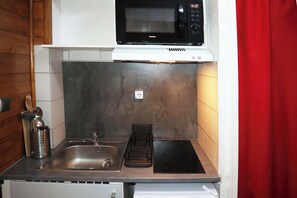 Eine kleine Küche mit Spüle, Herd und Mikrowelle.