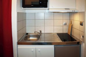 Eine kompakte Küche mit Mikrowelle, Spüle und integriertem Geschirrspüler.