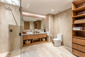 Un bany modern amb un espai de dutxa de vidre, un lavabo amb mirall i un vàter.