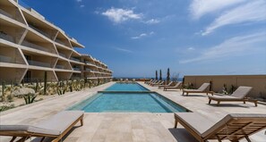 Una piscina amb gandules, un paisatge desèrtic i un edifici amb un disseny arquitectònic singular.