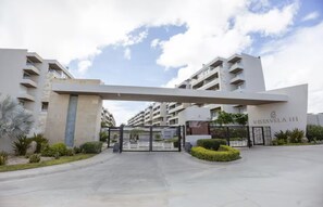 A modern apartment complex entrance with a gated driveway, a central archway, and a sign reading 'VISTA VELA III'. - Penthouse | Ocean Views, Pools & Padel Court (Cabo San Lucas)