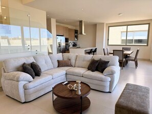 Ein modernes Wohnzimmer mit einem Ecksofa, einem Couchtisch und einem Essbereich mit Stühlen und einem Tisch.