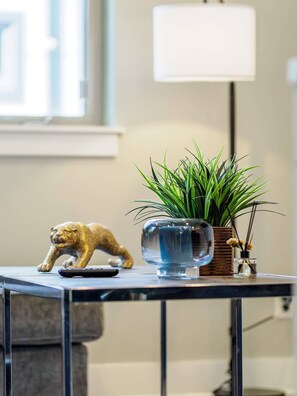 A small table with a glass vase, a potted plant, a remote control, and a decorative item.