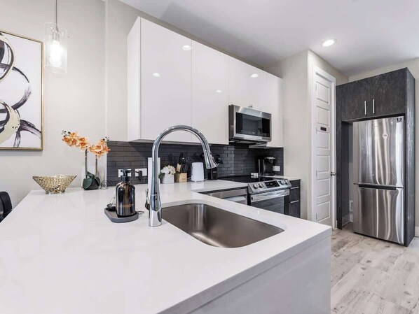 A modern kitchen with a large island, stainless steel appliances, and a minimalist design.