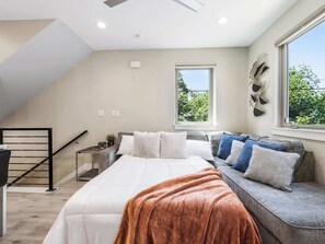 A bedroom with a bed, a bench with cushions, a window, and a staircase.