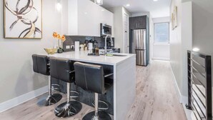 A modern kitchen with a central island, bar stools, and stainless steel appliances. - Modern Townhome Rooftop Garage Stockyards Downtown (Fort Worth)
