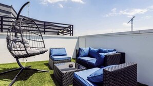 A rooftop patio with outdoor furniture, including a chair, sofa, and ottoman. - Modern Townhome Rooftop Garage Stockyards Downtown (Fort Worth)