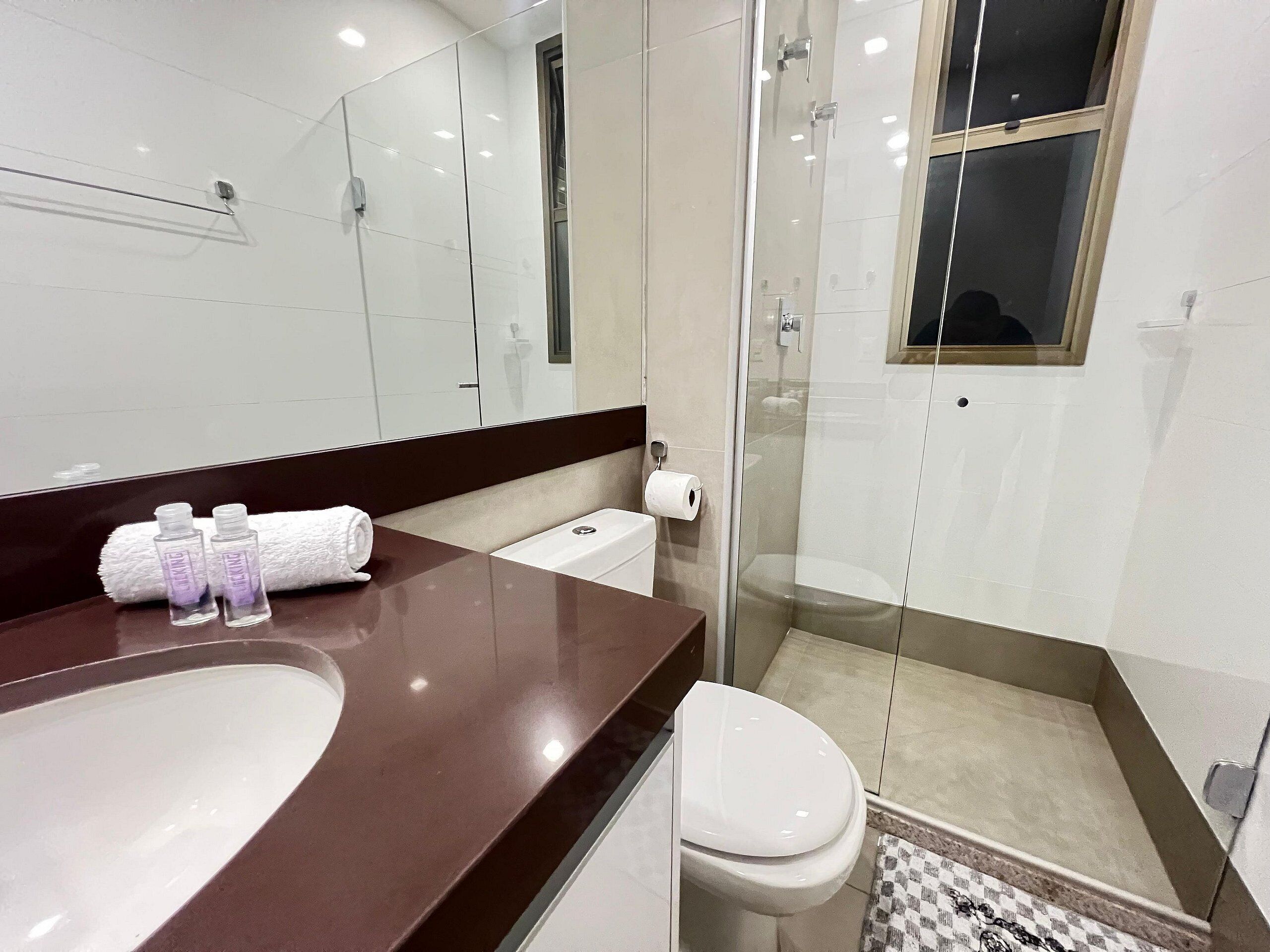 A modern bathroom with a large sink, toilet, and glass shower enclosure.