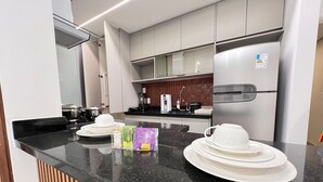 A modern kitchen with a black countertop, stainless steel appliances, and a tiled backsplash. - LK Savassi 6 (Belo Horizonte)