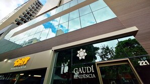 A modern building with a glass facade, a prominent 'GAUDI RESIDENCIA' sign, and a 'BARBEARIA' sign. - LK Savassi 6 (Belo Horizonte)