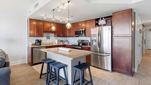 A modern kitchen with wooden cabinets, stainless steel appliances, and a central island with stools. - Resort Condo w/ Gulf Views, 5 Pools & Hot Tubs (Panama City Beach)