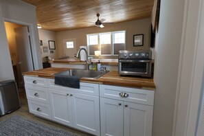 A kitchen with white cabinets, a wooden countertop, a built-in oven, and a ceiling fan. - 1 Br Suite in Downtown North Creek, with Views of Gore Mountain & Ski Bowl (North Creek)