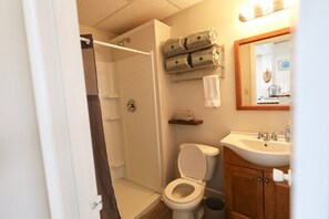 A bathroom with a shower, toilet, sink, and a towel rack with folded towels. - 1 Br Suite in Downtown North Creek, with Views of Gore Mountain & Ski Bowl (North Creek)