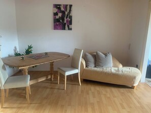 A dining area with a wooden table and chairs, a sofa, and a wall-mounted abstract painting. - Pure Relaxation Quiet and Cozy (Weyhausen)