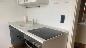 Una cocina compacta con horno integrado, cocina y lavamanos.