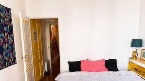 Ein Schlafzimmer mit einem Bett, einer roten Decke, einem Holzkopfende, einem Nachttisch und einer Lampe.