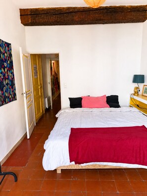 Ein Schlafzimmer mit einem Bett, einer roten Decke, einem Holzkopfende, einem Nachttisch und einer Lampe.