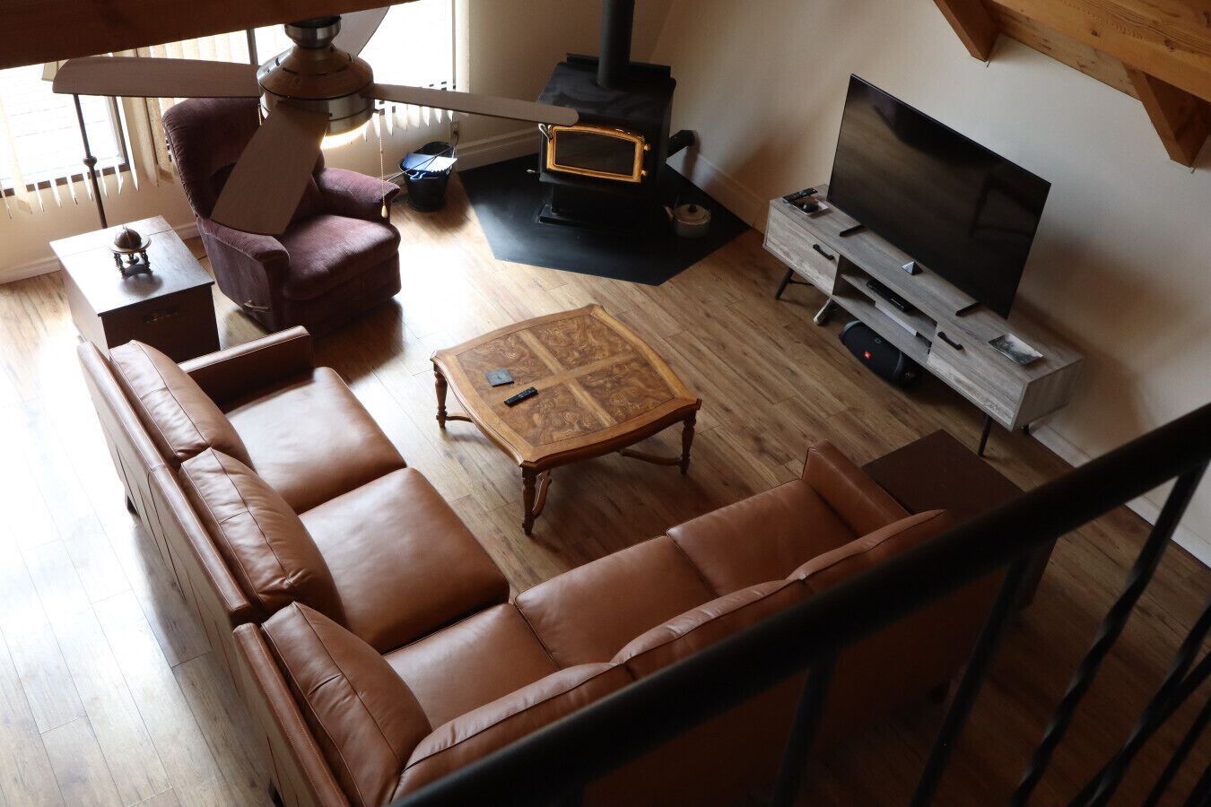 A living room with a sofa, a coffee table, a TV, a fireplace, and a staircase.