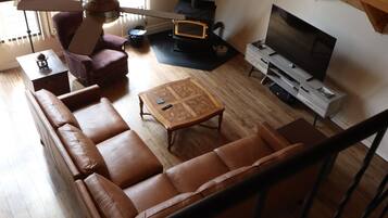 A living room with a sofa, a coffee table, a TV, a fireplace, and a staircase.