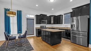 Una cocina moderna con armarios negros, electrodomésticos de acero inoxidable y una isla central.