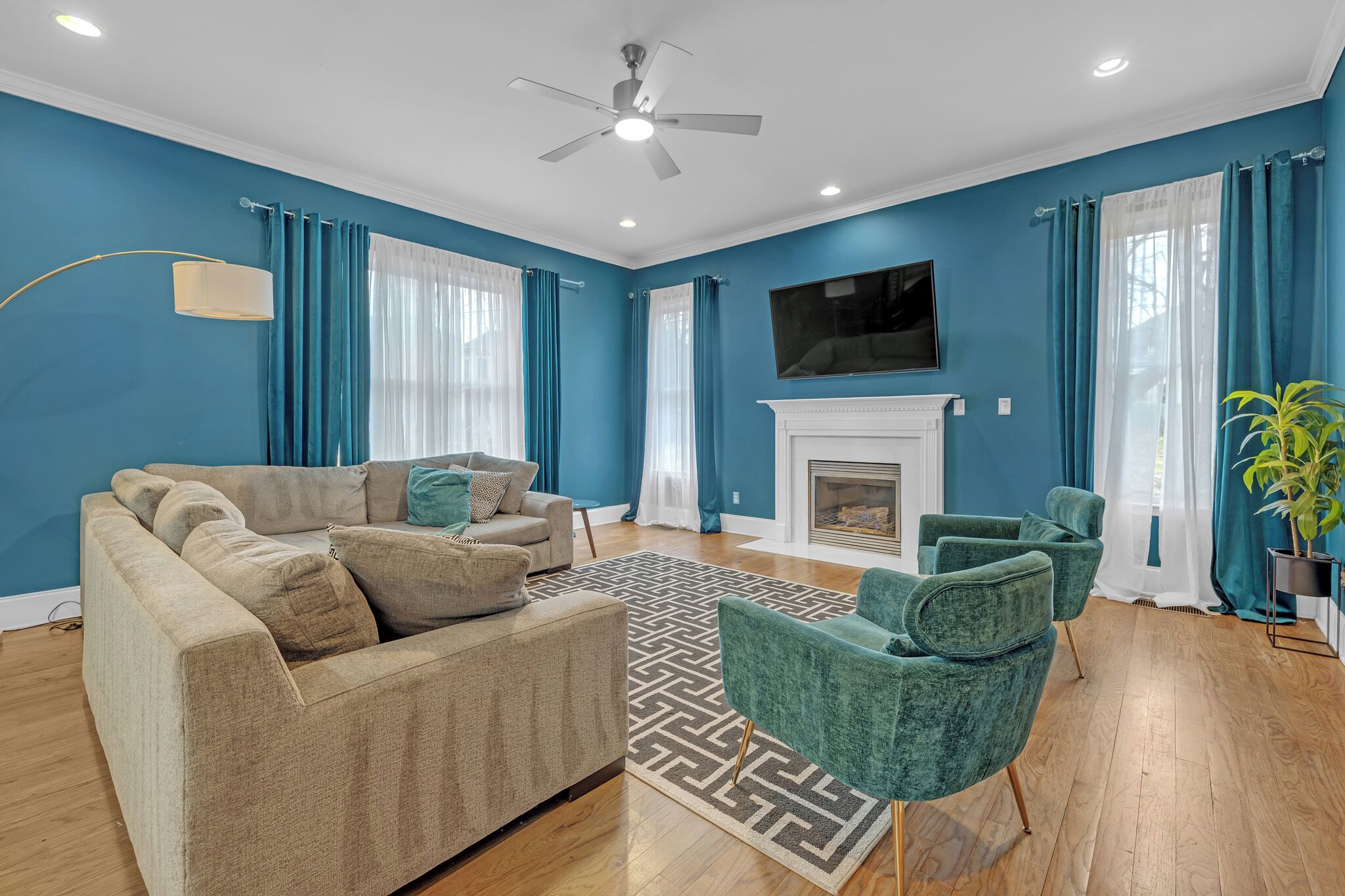 A living room with a sofa, armchairs, a fireplace, and a ceiling fan.