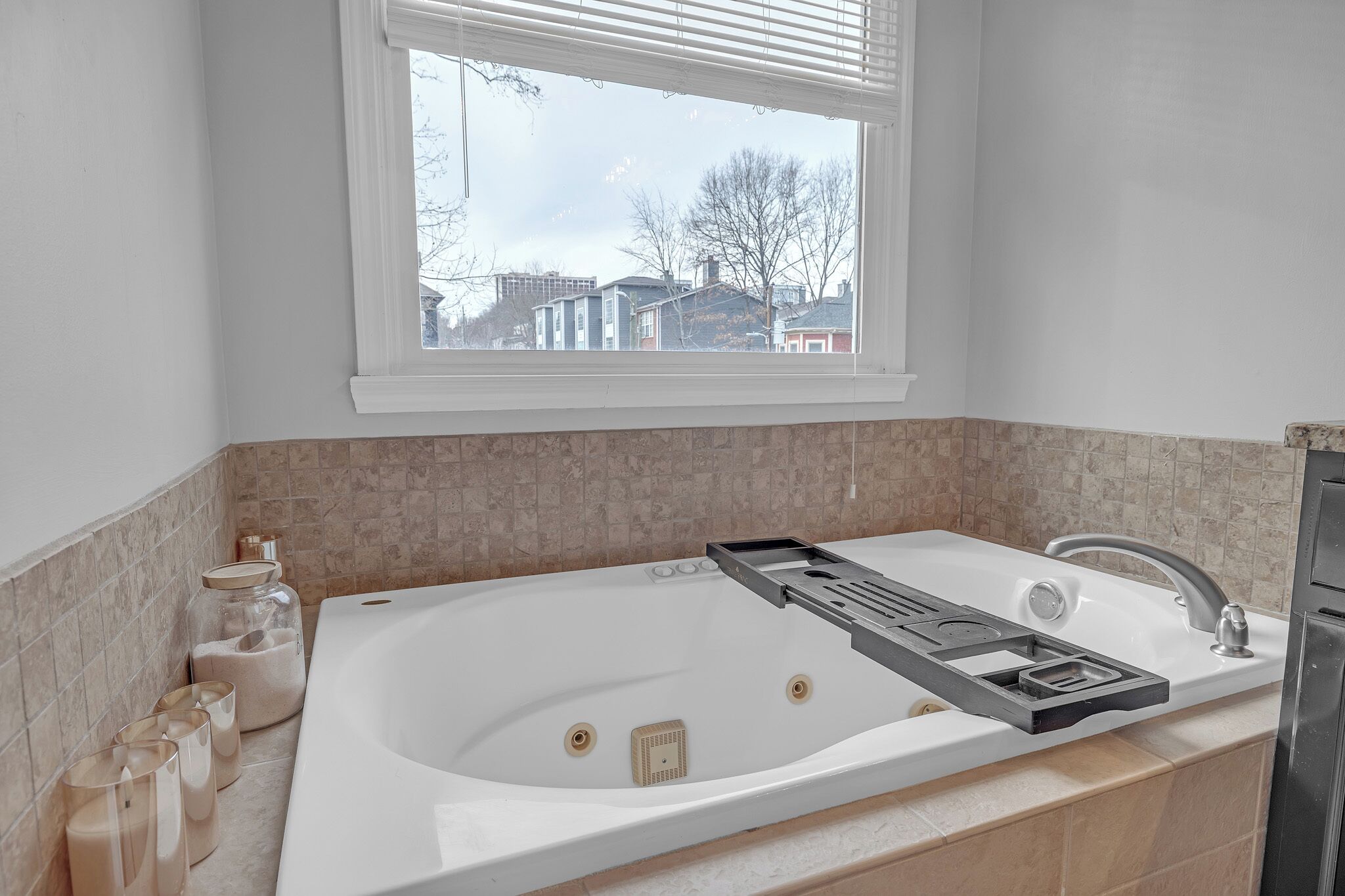 Une salle de bain avec une grande baignoire, une fenêtre et une vue sur les bâtiments environnants.