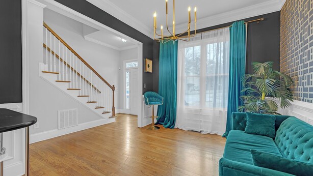 Una sala de estar moderna con una escalera, un sofá color turquesa y una araña.