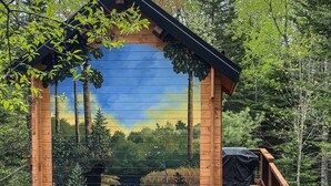 A wooden cabin with a deck and a mural of a landscape. - Cozy Loft Bunkie | Sleeps 4 | BBQ + Fire Pit (Mount Uniacke)