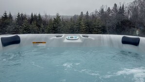 A hot tub with a control panel, surrounded by a forest. - Cozy Loft Bunkie | Sleeps 4 | BBQ + Fire Pit (Mount Uniacke)