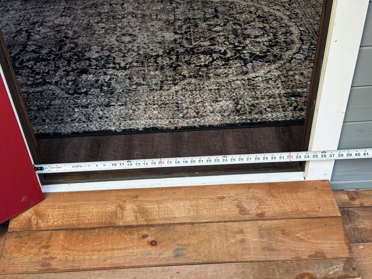 A wooden door threshold with a measuring tape.