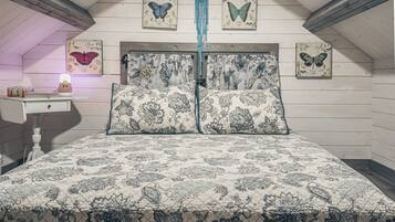 Une chambre à coucher avec une couvre-lit à motifs, des poutres en bois au plafond et des décorations murales sur le thème des papillons.