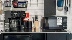 Una kitchenette equipada con cafetera, microondas y cajones para guardar objetos.