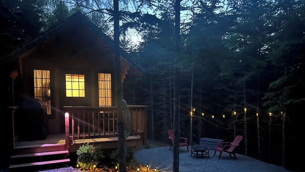 A cabin with a porch, outdoor seating, and string lights. - Pet-Friendly Cabin | Sleeps 2 | Private Fire Pit (Mount Uniacke)