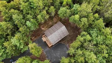 A small, rectangular building with a sloped roof surrounded by dense green trees.