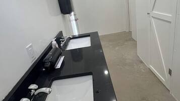 Un bany amb dues dutxes, un assecador de mans i un aparell d'aire condicionat.