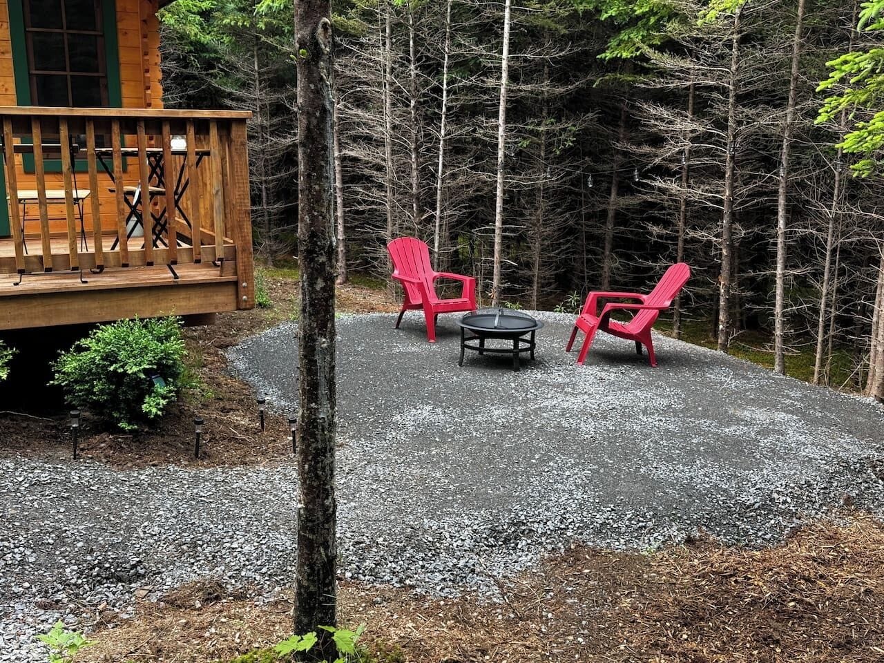 A wooden deck with outdoor seating, surrounded by a forest.