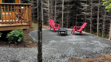 A wooden deck with outdoor seating, surrounded by a forest.