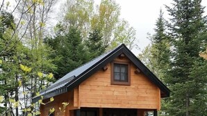 A wooden cabin with a balcony, a door, and windows. - Private 4 Cabin Retreat | Hot Tub | Tiny Cabins (Mount Uniacke)