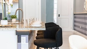 A modern kitchen with a bar area, a sink, and a door leading to another room. - Immersive Rooms • Gaming Lounge • Summerville (Kissimmee)