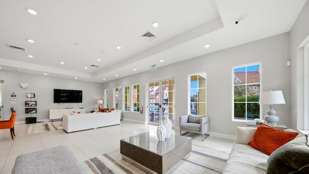 A modern living room with a white sofa, a coffee table, and a TV. - Immersive Rooms • Gaming Lounge • Summerville (Kissimmee)
