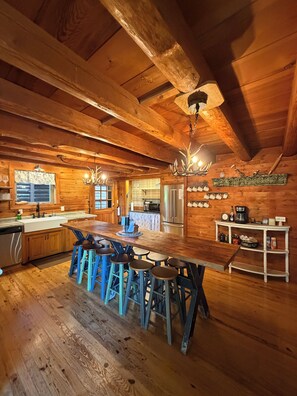 A rustic wooden interior with a bar area, stools, and a kitchen with modern appliances. - Ozark Private Cabin, sleeps 12, on 6+ acres, Close to Dogwood Canyon & Branson (Lampe)