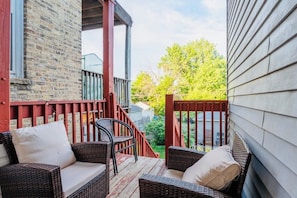 A covered porch with wicker furniture and a red railing.