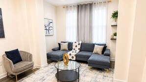 Ein Wohnzimmer mit Ecksofa, einem runden Couchtisch und einem Teppich.
