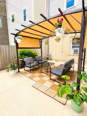 A covered patio area with outdoor furniture, a pergola, and hanging planters.