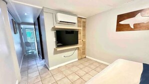 Ein Zimmer mit einem Bett, einem Fernseher und einer Wandklimaanlage.