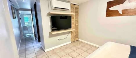 A room with a bed, a TV, and a wall-mounted air conditioner.
